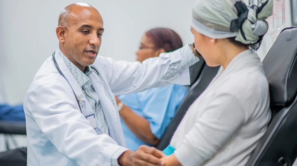 Ārsts konsultē pacientu Rīgas 1. slimnīcā, fonā redzama medicīnas māsa.