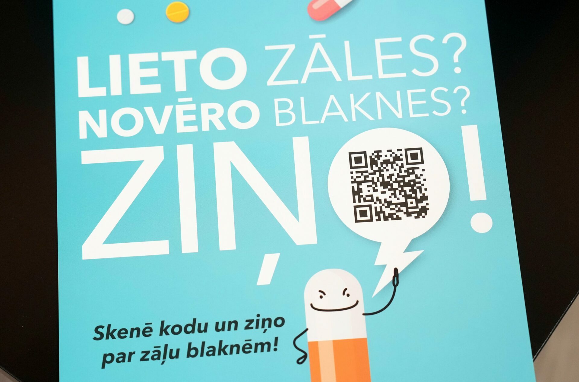 Plakāts ar tekstu "LIETO ZĀLES? NOVĒRO BLAKNES? ZINI!" un QR kodu, kas aicina ziņot par zāļu blaknēm.
