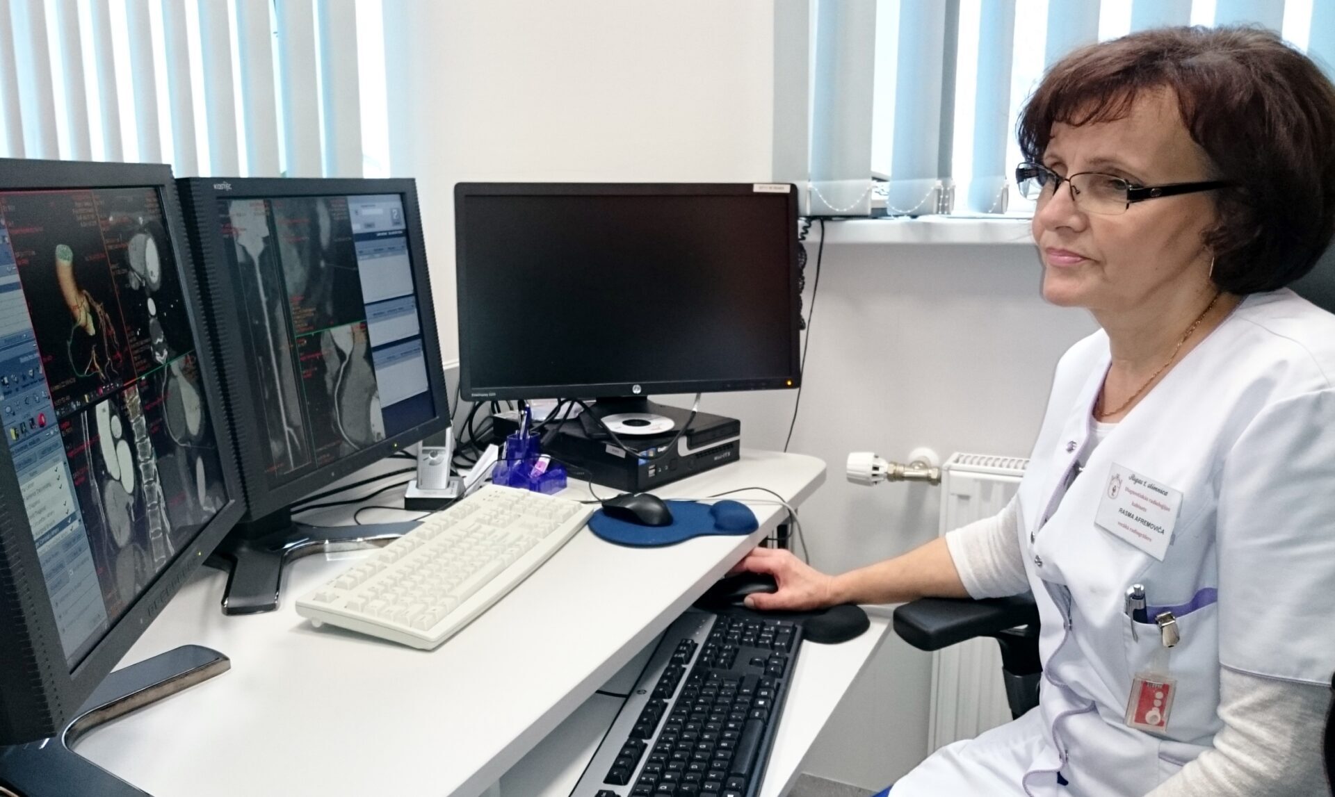 Ārsts pie datora, analizējot medicīniskos attēlus uz diviem monitoriem Rīgas 1. slimnīcā.