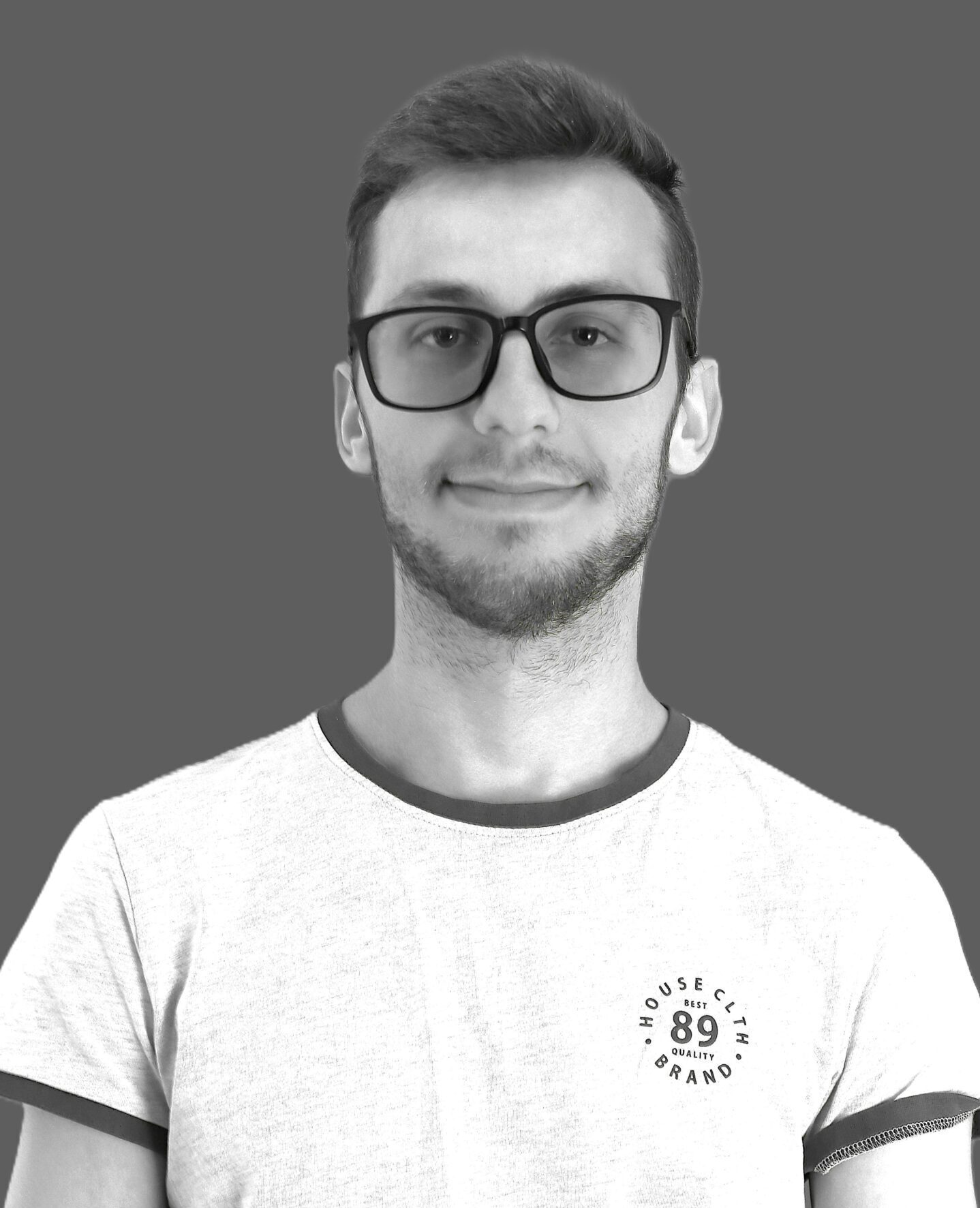 Jauns vīrietis ar brillēm, pelēkā T-kreklā ar uzrakstu 