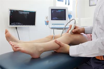 Ārsts veic ultraskaņas izmeklējumu bērna kājai Rīgas 1. slimnīcā. Fons ar medicīnas iekārtām.