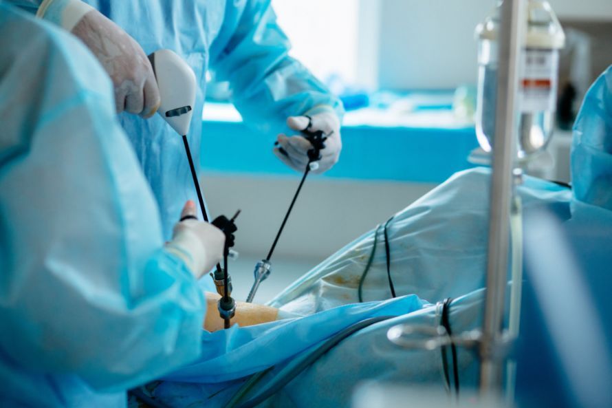 Ārsti veic operāciju, izmantojot medicīniskos instrumentus, pacientam uz operāciju galda.