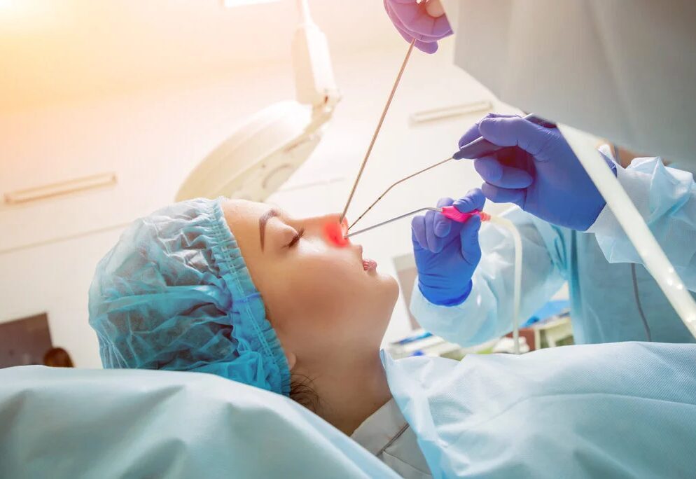 Sieviete operācijas laikā, ārsti veic procedūru uz deguna, izmantojot medicīniskos instrumentus.