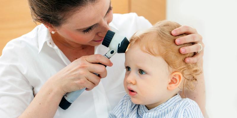 bērnu dermatologs veic ādas pārbaudi ar dermatoskopu bērnam dermatologa konsultācijas laikā