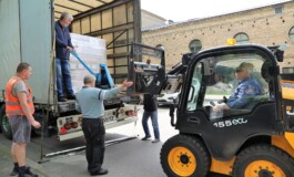 Kravas izkraušana Rīgas 1. slimnīcā, darbinieki strādā ar iekrāvēju un palīgierīcēm.