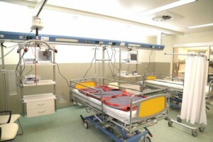 Slimnīcas telpa ar divām gultām, medicīnas iekārtām un aizkaru nodalījumu. Rīgas 1. slimnīca.