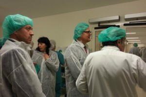 Cilvēki medicīniskās drēbēs un cepurēs Rīgas 1. slimnīcā, sarunājoties un gatavojoties darbam.