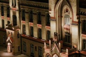 Rīgas 1. slimnīcas ēka naktī, apgaismota, ar modernu gaismas instalāciju priekšā.
