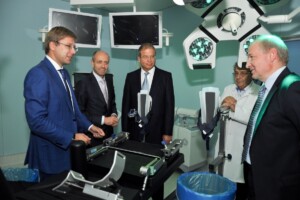 Četri vīrieši un ārsts apspriež medicīnas iekārtas operāciju telpā Rīgas 1. slimnīcā.