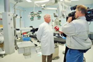 Ārsts intervijā operāciju zālē, fons ar medicīnas iekārtām un apgaismojumu. Rīgas 1. slimnīca.
