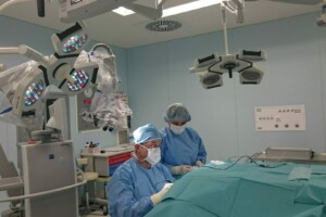 Divi ķirurgi operācijas telpā, strādājot pie operācijas uz galda ar medicīnas aprīkojumu.