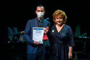 09.12.2021 Gada balva sociālajā nozarē Vīrietis ar masku saņem balvu "Gada balva sociālajā nozarē" no sievietes. Attēlā redzama arī diploma informācija.