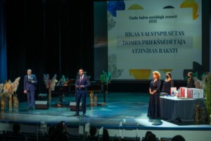 09.12.2021 Gada balva sociālajā nozarē Pasākums "Gada balva sociālajā nozarē 2021". Rīgas domes priekšsēdētāja atzinības raksti. Skatuve ar runātājiem.