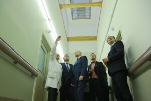 RD_komis_slimn_20160129 Grupas cilvēku, tostarp ārsts baltā mētelī, skatās uz griestiem Rīgas 1. slimnīcā.