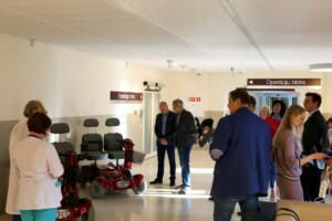Rīgas 1. slimnīcas gaiteņi ar cilvēkiem un elektriskajiem ratiņkrēsliem, redzams "Operāciju bloks" norādījums.