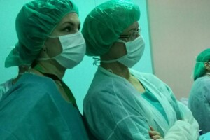 cof Divas sievietes medicīnas tērpos ar zaļām cepurēm un maskām, skatās uz priekšu. Rīgas 1. slimnīca.