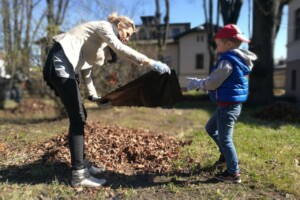 edf Sieviete un bērns kopā vāca lapas, izmantojot melnu maisu, saulaina diena Rīgas 1. slimnīcas teritorijā.