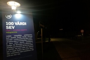 sdr Zīme "100 vārdi sev" Rīgas 1. slimnīcas pagalmā, norāda uz hologrāfisku projektu un pasākumu.