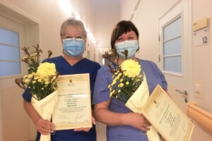 dav Divas sievietes medicīnas darbinieces ar ziediem un atzinības rakstiem Rīgas 1. slimnīcā. Redzami vārdi "Pateicības
