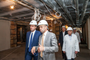 Būvniecības vieta Rīgas 1. slimnīcā, cilvēki ar ķiverēm, pārvietojas pa renovējamu telpu.
