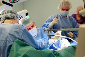 Ķirurgi veic operāciju, tērpti medicīniskajā apģērbā un maskās, Rīgas 1. slimnīcā.