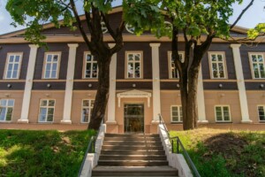 Rehabilitācijas klīnika ar ieeju pa kāpnēm un kokiem priekšā. Rīgas 1. slimnīca.