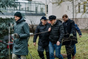 Vīrieši pārvieto koku Rīgas 1. slimnīcas teritorijā, apgādāti ar siltām drēbēm un darba rīkiem.