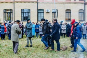 Pasākums Rīgas 1. slimnīcas pagalmā, cilvēki pulcējušies, daži vīrieši veic aktivitātes.