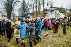 Cilvēki svin pasākumu ārā, dejotāji un mūziķi pie ugunskura Rīgas 1. slimnīcas teritorijā.