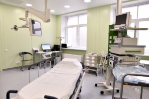 rd_1slimnica_20160418 Mediķu telpa ar gultu, monitoru, datoru un medicīnas iekārtām Rīgas 1. slimnīcā. Zaļas sienas un logi.