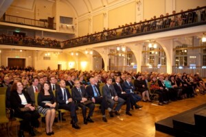 Pasākums ar lielu auditoriju, cilvēki sēž zālē un skatās uz skatuvi. Rīgas 1. slimnīca.